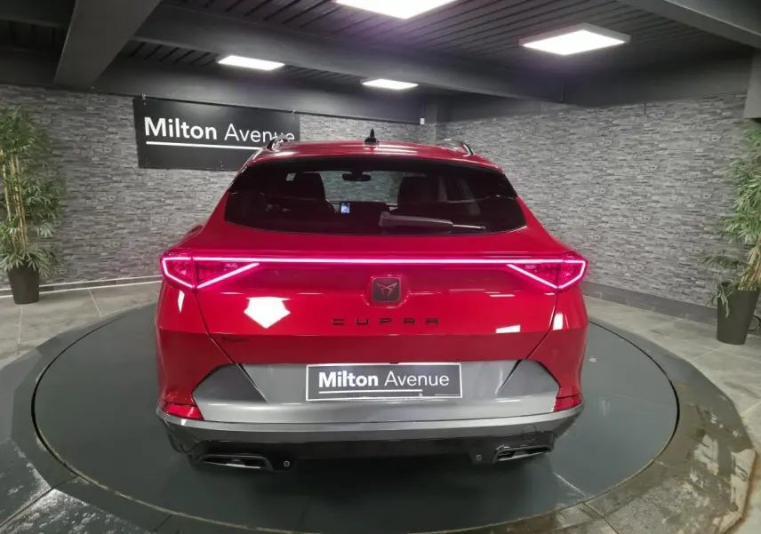 Vue arrière d'une CUPRA Formentor rouge avec bandeau lumineux LED et double sortie d'échappement noire.
