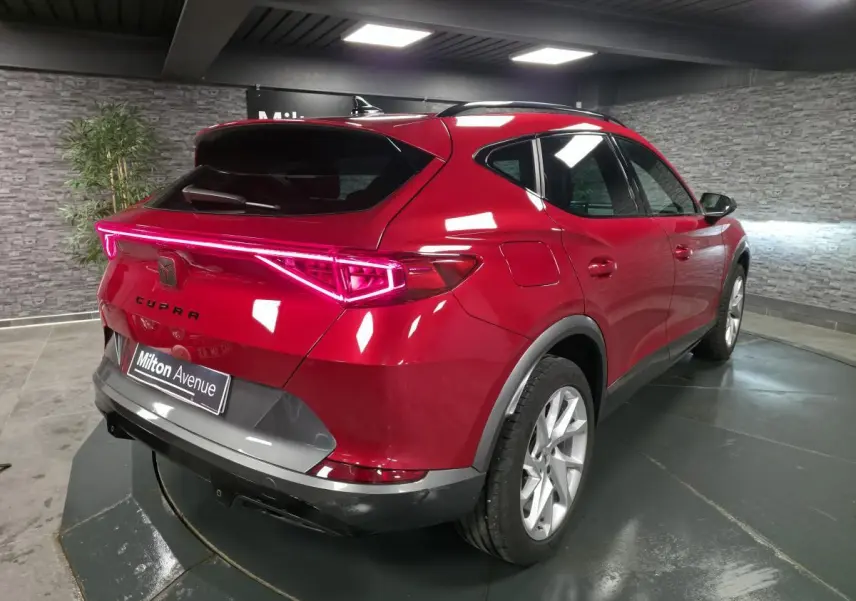 Vue 3/4 arrière droite du CUPRA Formentor rouge avec bandeau lumineux arrière et jantes alliage 18 pouces.