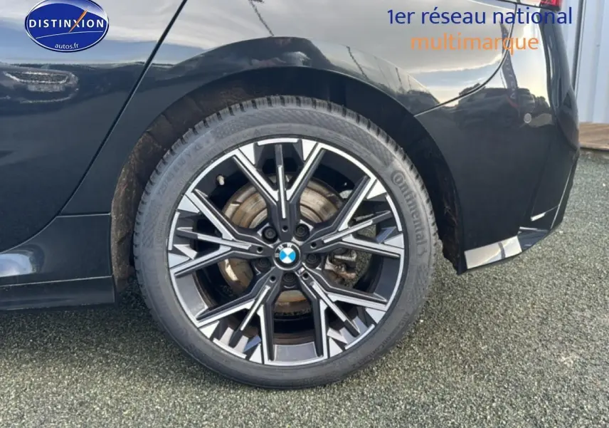 Gros plan sur la roue arrière droite noire d'une BMW Série 1 120da 2024 avec jante alu multibranches.