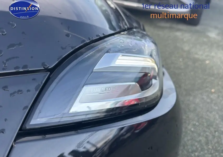Gros plan sur le phare avant droit LED d’une BMW Série 1 noire (f70) 120da 2024, avec gouttes d’eau visibles.