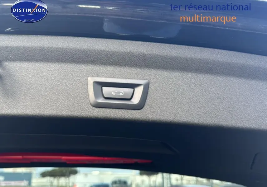 Bouton d'ouverture électrique du coffre sur la partie intérieure du hayon d'une BMW Série 1 noire, vue de l'arrière ouvert.
