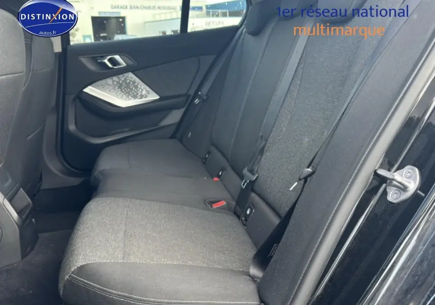 Vue côté droit de la banquette arrière en tissu anthracite dans une BMW Série 1 noire, porte ouverte.