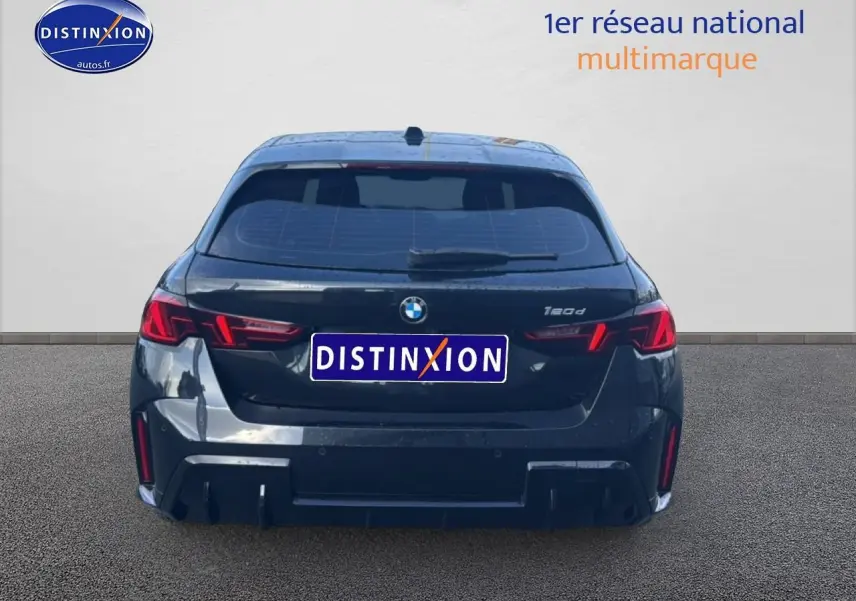 Vue arrière d'une BMW Série 1 noire 2024 avec feux LED et logo distinctif au centre du hayon.