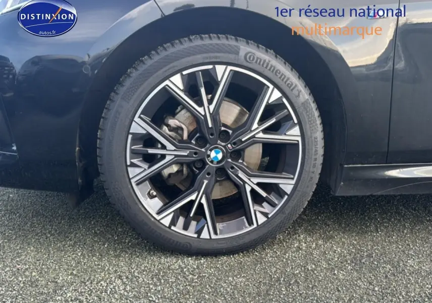Gros plan sur la roue arrière droite noire d'une BMW Série 1 120da 2024 avec jante alliage multibranches.