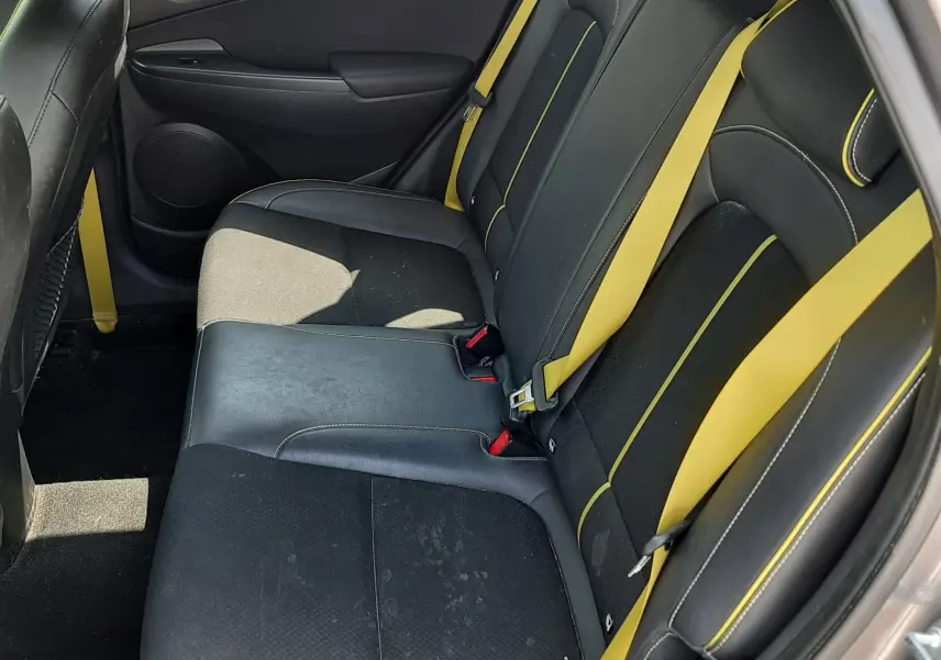 Vue intérieure arrière droite du Hyundai Kona gris 2018, sièges noirs avec surpiqûres et ceintures jaunes distinctives.
