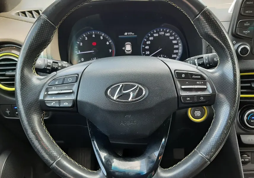 Vue rapprochée du volant en cuir noir du Hyundai Kona 2018, avec commandes intégrées et bouton start/stop visible.