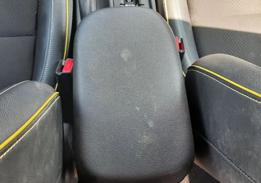 Gros plan sur l'accoudoir central noir avec surpiqûres jaunes, entre les sièges avant du Hyundai Kona gris.