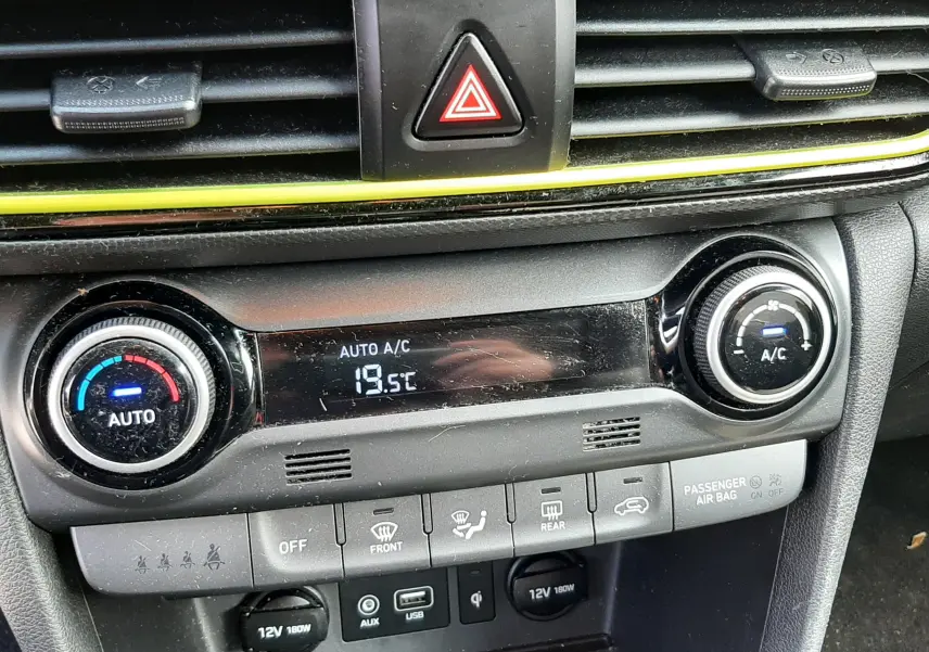 Vue rapprochée de la console centrale du Hyundai Kona gris, montrant la climatisation automatique et les commandes de ventilation.