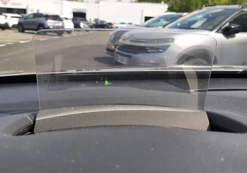 Vue intérieure du tableau de bord du Hyundai Kona 2018, avec affichage tête haute transparent et parking en arrière-plan.