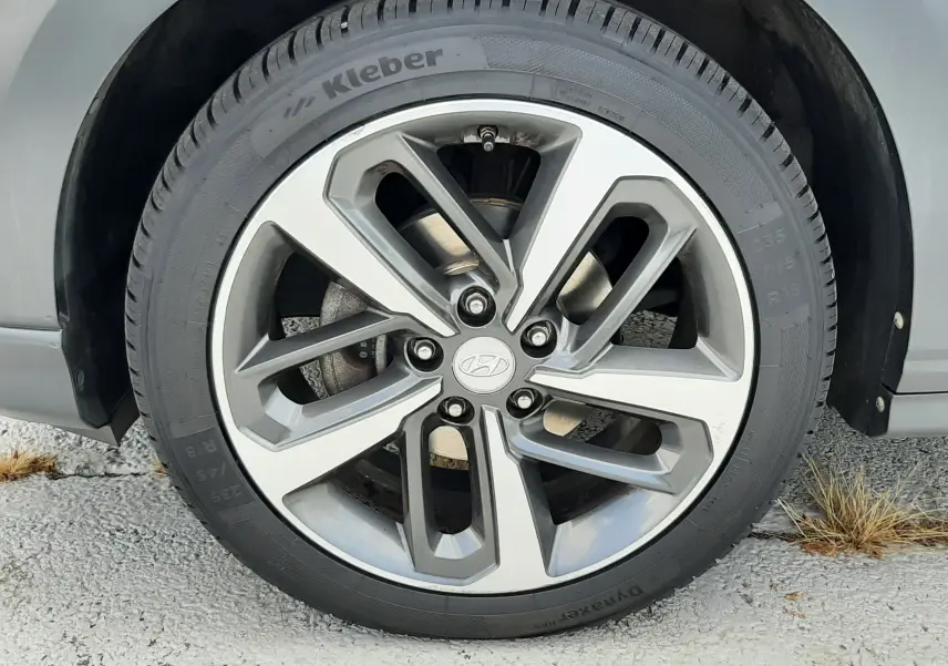 Gros plan sur la roue avant gauche d'une Hyundai Kona gris, avec jante alliage à cinq branches doubles.