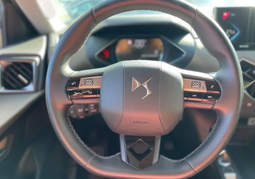Vue rapprochée du volant cuir noir du DS3 Crossback E-Tense 2021 avec commandes intégrées et logo DS central.