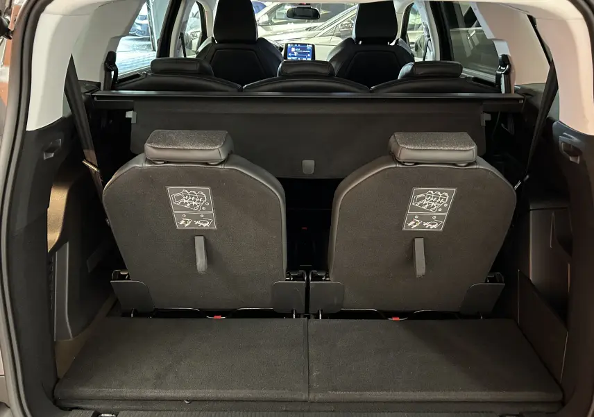 Vue arrière du coffre ouvert d'un Peugeot 5008 gris 2020, montrant les dossiers des sièges arrière relevés et l'intérieur spacieux.