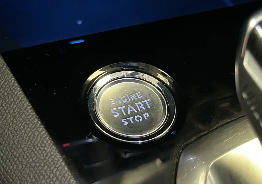 Bouton poussoir "Engine Start Stop" en gros plan sur la console noire brillante du Peugeot 5008 gris 2020.