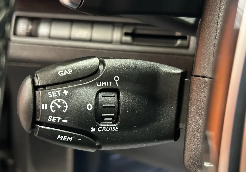 Gros plan sur la commande de régulateur de vitesse du Peugeot 5008 gris, montrant les boutons de réglage et limiteur.