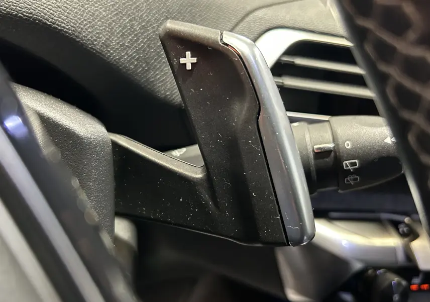 Gros plan sur la palette de changement de vitesse "+" côté droit du volant dans l'habitacle du Peugeot 5008 gris 2020.