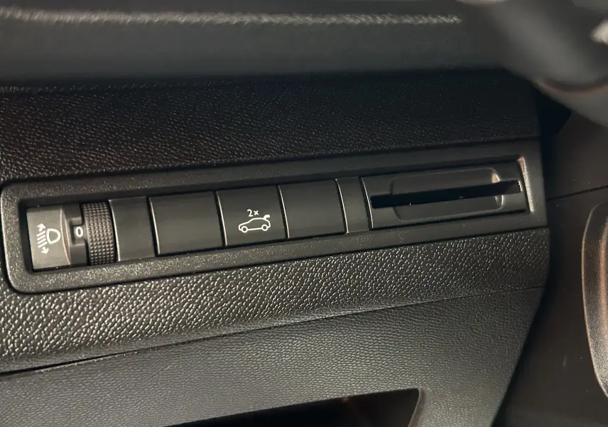 Détail intérieur montrant les commandes noires du tableau de bord du Peugeot 5008 gris, avec bouton hayon et réglage phare.