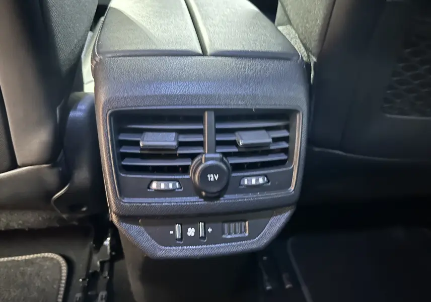 Gros plan sur la console arrière noire du Peugeot 5008 2020 avec bouches d'aération et prise 12V visible.