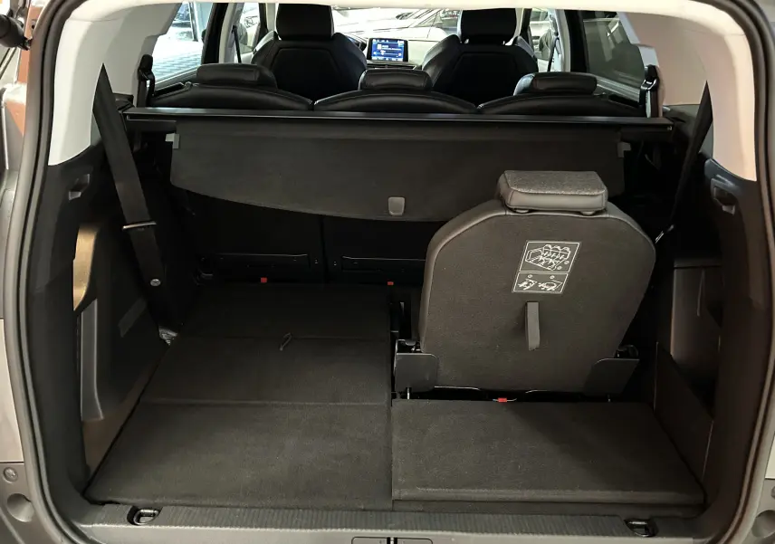 Coffre ouvert du Peugeot 5008 gris, vue arrière montrant banquette arrière partiellement rabattue et espace de chargement.