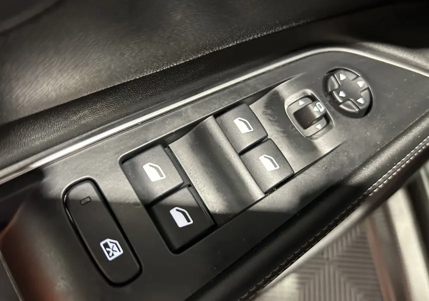 Gros plan sur les commandes de lève-vitres et réglage des rétroviseurs côté conducteur du Peugeot 5008 gris 2020.