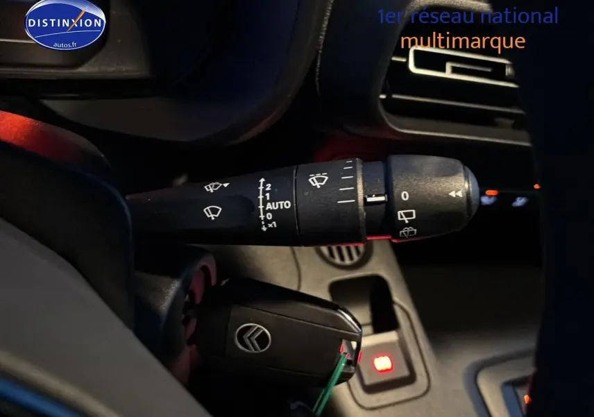 Gros plan sur la commande d’essuie-glace et la clé de contact du Citroën Berlingo Fourgon blanc, intérieur conducteur.