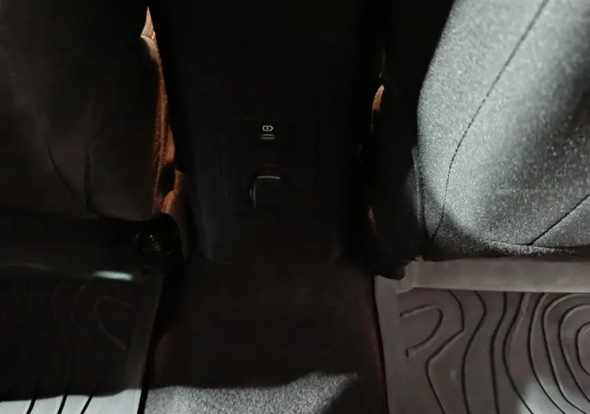 Prise USB et prise 12V visibles entre les sièges arrière noirs de la Dacia Sandero Extreme+ TCe 110 2024.