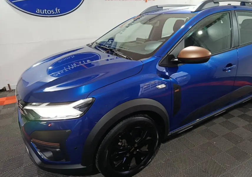 Vue 3/4 avant droite d'une Dacia Sandero Extreme+ TCe 110 bleu avec rétroviseurs bronze et jantes noires.