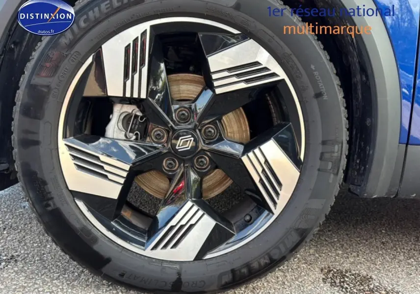 Gros plan sur la roue avant droite du Renault Symbioz bleu iron metal, jante noire et argentée au design moderne.