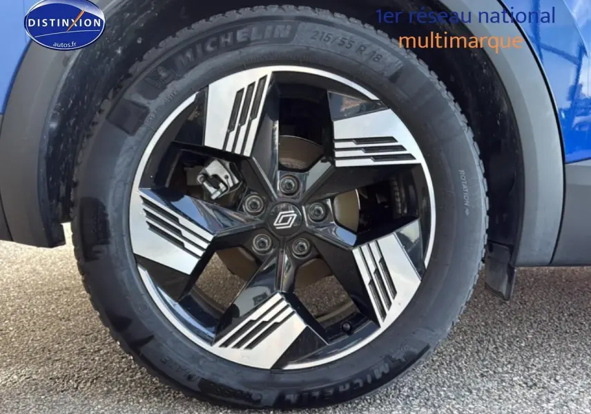 Gros plan sur la roue avant droite du Renault Symbioz bleu iron metal, jante alliage noire et argentée au design géométrique.