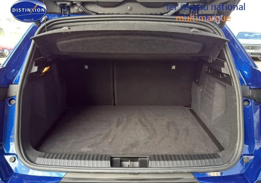 Coffre ouvert vu de l'arrière d'une Renault Symbioz bleu iron metal, espace de chargement vide et tapis gris.