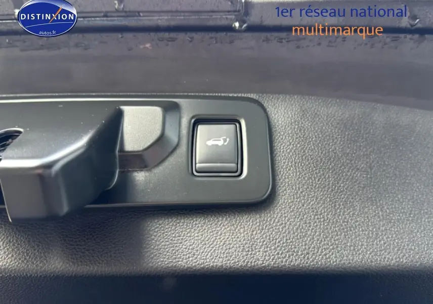 Bouton d'ouverture du coffre en gros plan sur panneau intérieur noir du Renault Symbioz bleu iron metal.