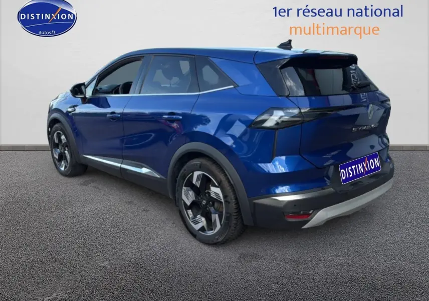 Vue 3/4 arrière gauche d’un Renault Symbioz bleu iron metal avec vitres arrière surteintées et jantes distinctives.