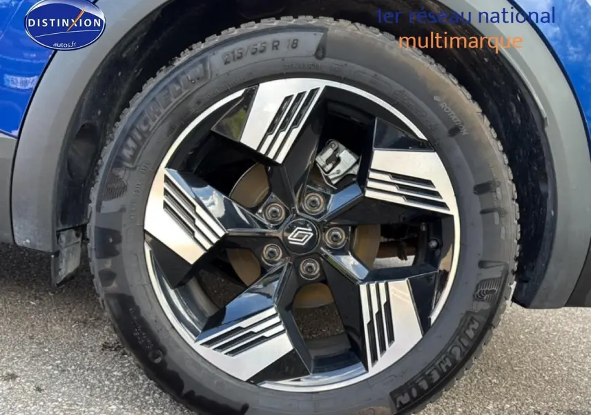 Gros plan sur la roue avant droite d'une Renault Symbioz bleu iron metal avec jante noire et argentée design moderne.