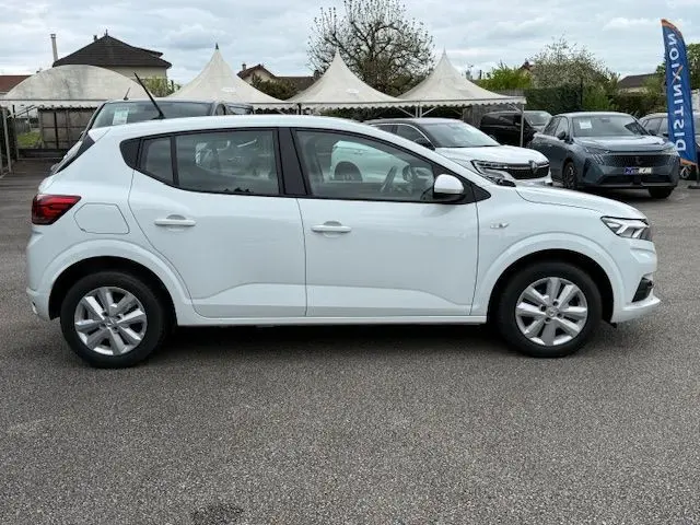 Vue latérale droite d'une Dacia Sandero blanc glacier 2023, compacte et moderne sur un parking extérieur.