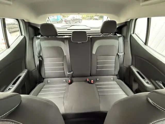 Vue intérieure arrière des sièges noirs et gris du Dacia Sandero 2023, avec ceintures de sécurité et appuie-têtes visibles.
