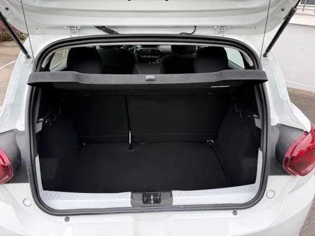 Vue arrière du coffre ouvert d'une Dacia Sandero blanc glacier 2023, montrant l'espace de chargement vide.
