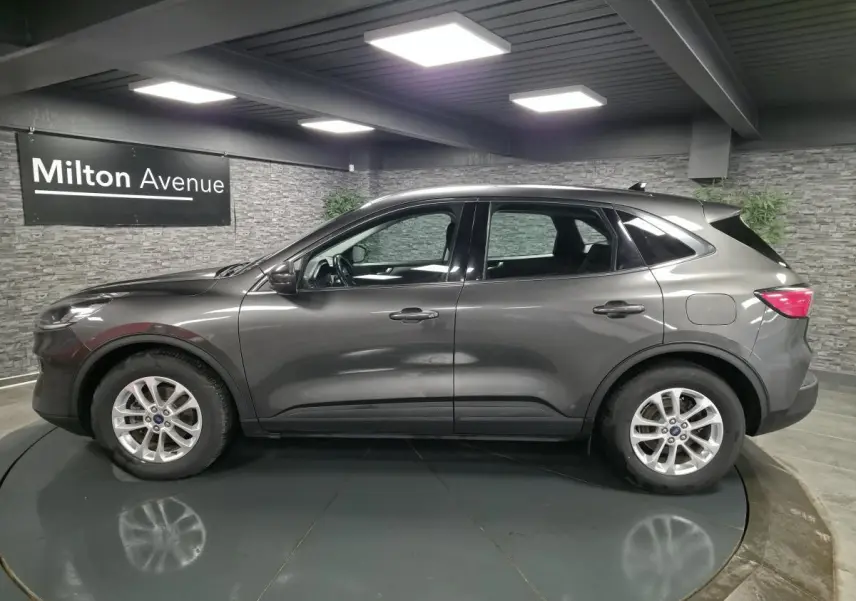 Ford Kuga gris métallisé vue de profil côté gauche dans un showroom avec jantes alliage 17 pouces.