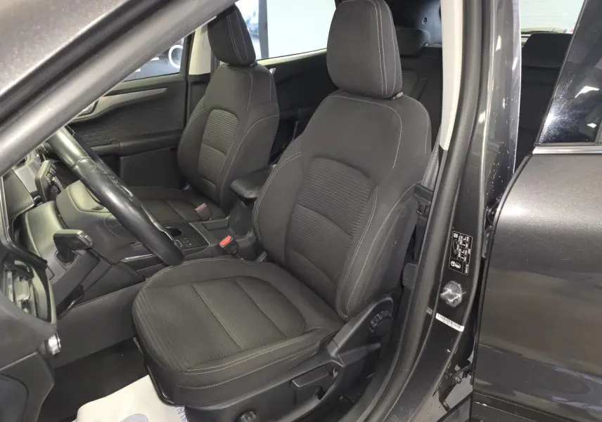 Vue intérieure côté conducteur du Ford Kuga gris 2020, sièges tissu noir avec coutures contrastées.