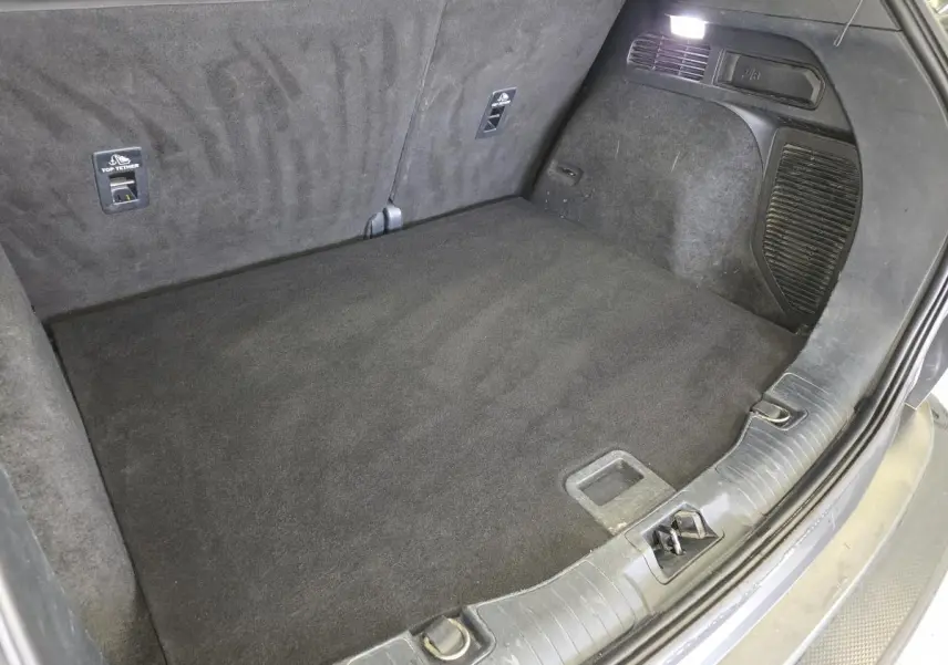 Coffre spacieux et propre du Ford Kuga gris, vue intérieure arrière avec éclairage et fixations Isofix visibles.