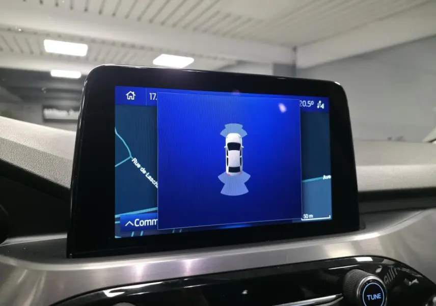Écran tactile central du Ford Kuga gris 2020 affichant l'aide au stationnement avec vue du véhicule en plan dessus.