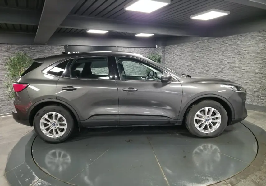 Vue latérale droite d'un Ford Kuga gris métallisé 2020 avec jantes alliage 17 pouces en intérieur showroom.
