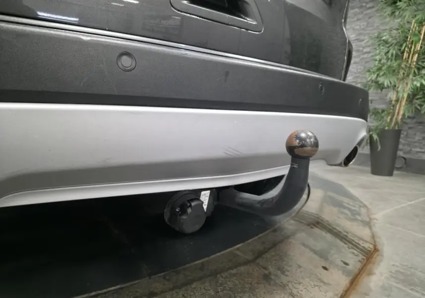 Gros plan sur l'attelage fixe arrière d'un Ford Kuga gris 2020, avec prise électrique visible sous le pare-chocs.