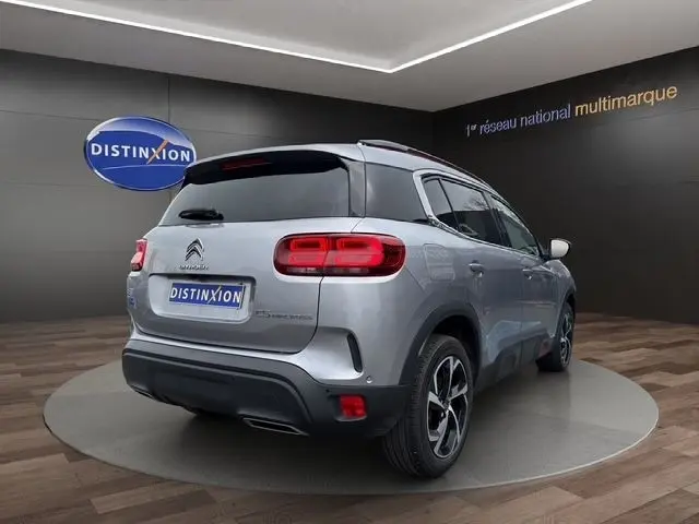 Vue 3/4 arrière droite d'un Citroën C5 Aircross gris clair avec feux LED et jantes alliage noires et argentées.