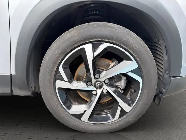 Gros plan sur la roue avant droite gris clair du Citroën C5 Aircross avec jante alliage noire et argentée au design moderne.