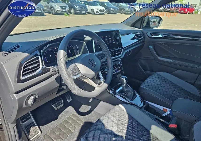 Intérieur avant du Volkswagen T-Roc noir perle, volant cuir multifonction et sièges tissu R-Line avec surpiqûres croisées.