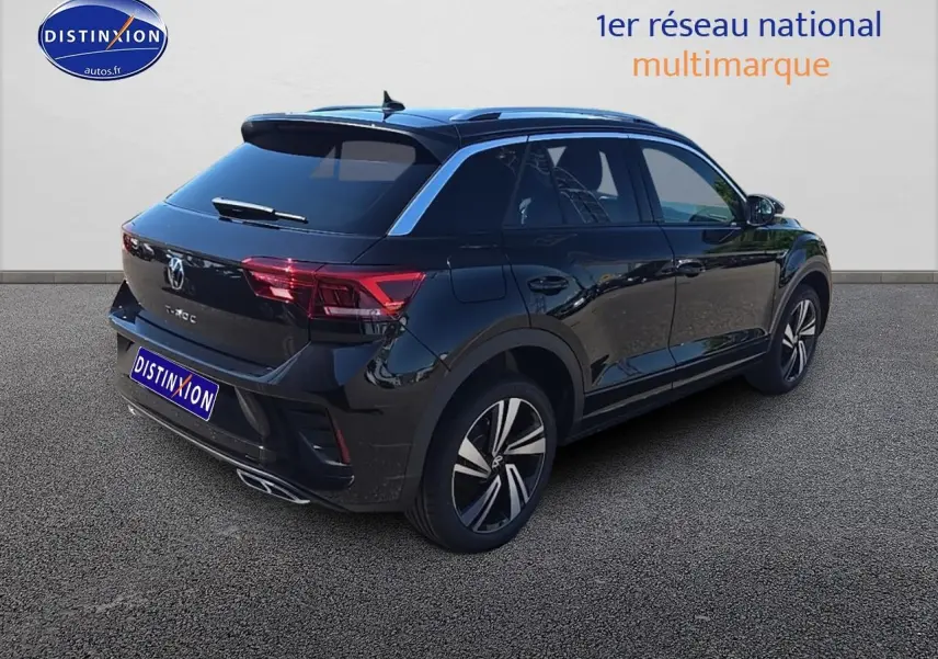 Volkswagen T-Roc noir perle en 3/4 arrière droit, avec jantes alliage et barres de toit argentées visibles.