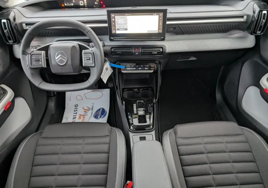 Intérieur avant du Citroën C3 Aircross 2025, tableau de bord gris clair avec écran tactile et volant multifonctions noir.