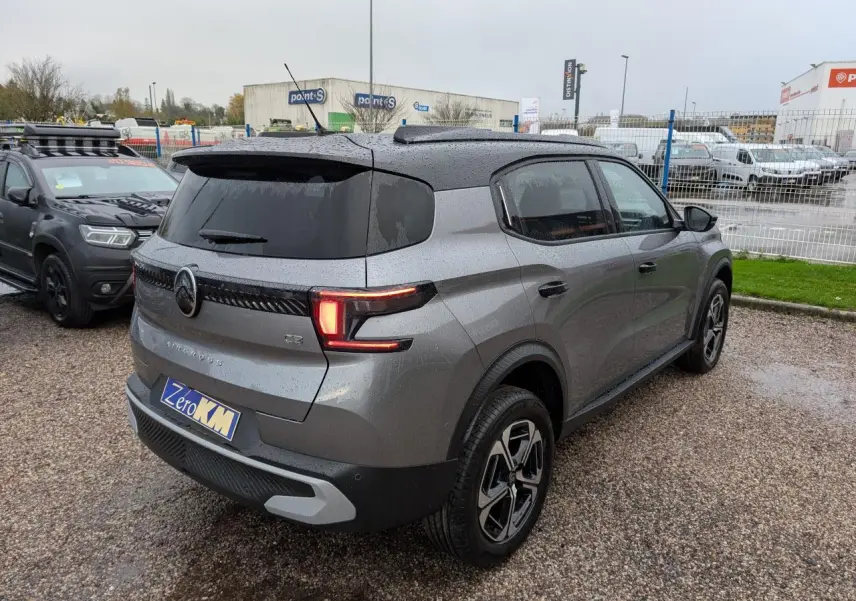 Vue 3/4 arrière droite d'un Citroën C3 Aircross gris métallisé avec toit noir et feux arrière LED allumés.