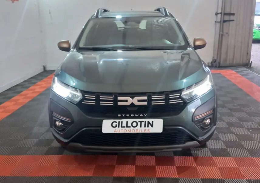 Vue avant d'une Dacia Sandero Extreme+ TCe 110 2024 vert, avec phares LED allumés et calandre noire distinctive.