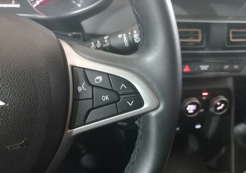 Gros plan sur le volant cuir synthétique noir de la Dacia Sandero Extreme+ 2024 avec commandes multifonctions visibles.