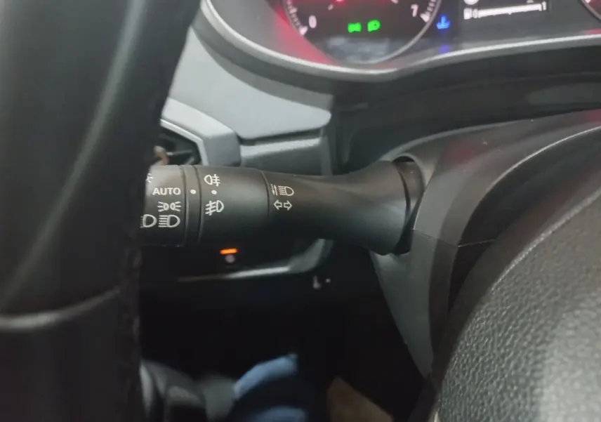 Gros plan sur la manette de commande des phares et clignotants du tableau de bord d'une Dacia Sandero 2024, intérieur noir.